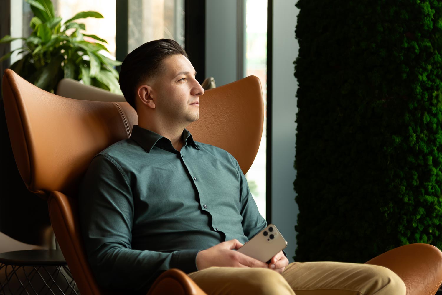 Compax Telco specialist sitting on armchair with mobile phone in his hand